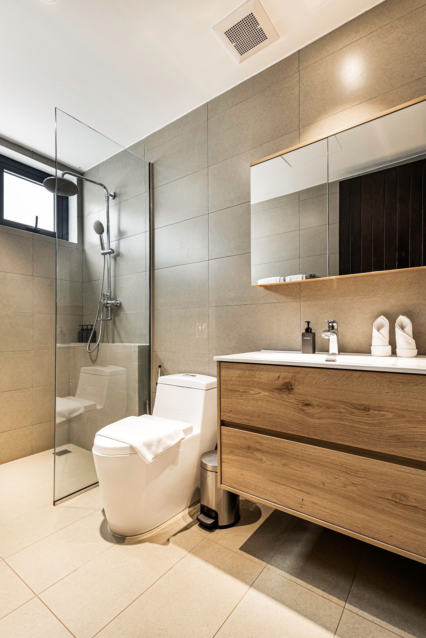 Modern bathroom with shower, toilet, and wooden vanity with sink and mirror