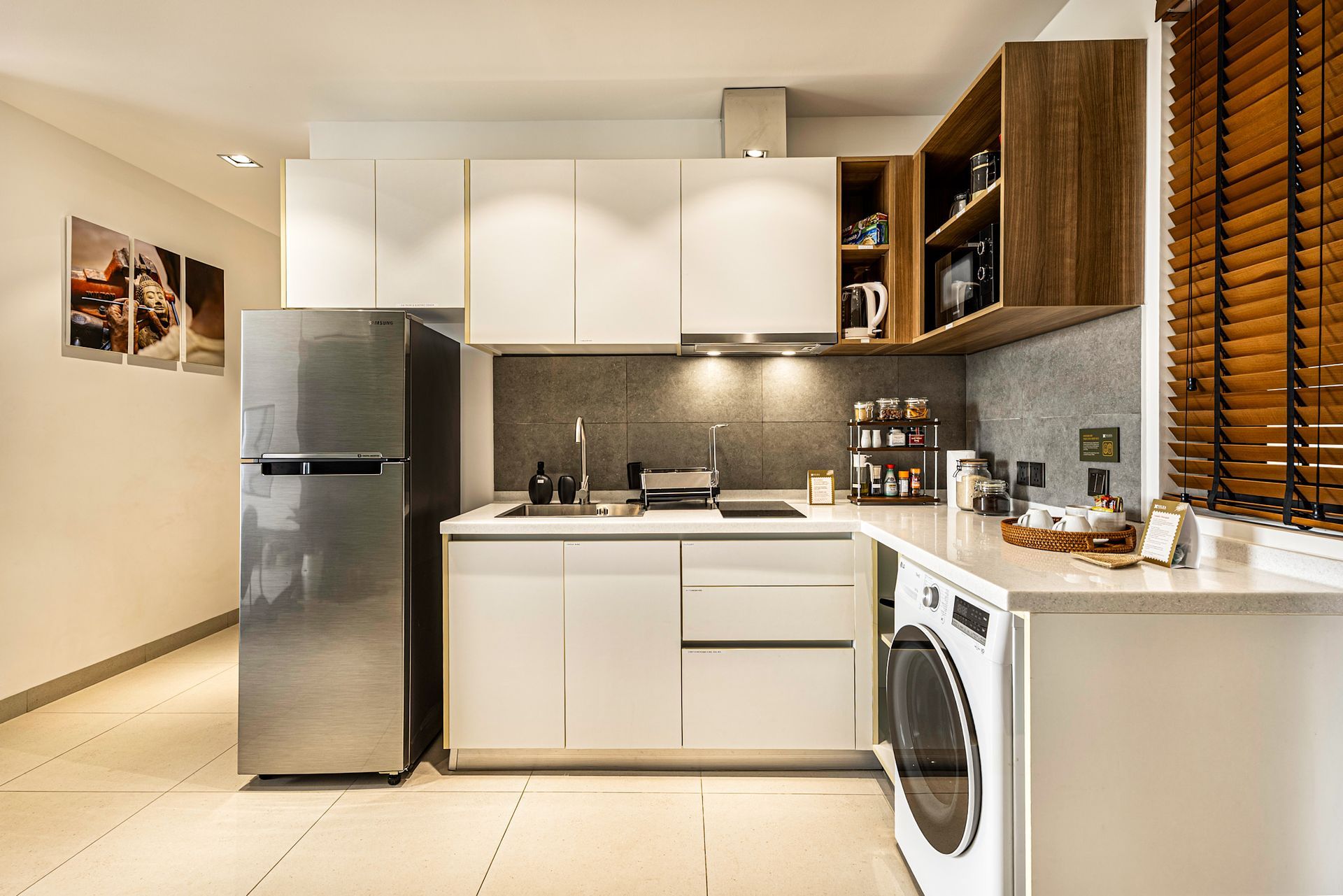 Modern kitchen with white cabinets, stainless steel fridge, black backsplash, and washing machine under the counter