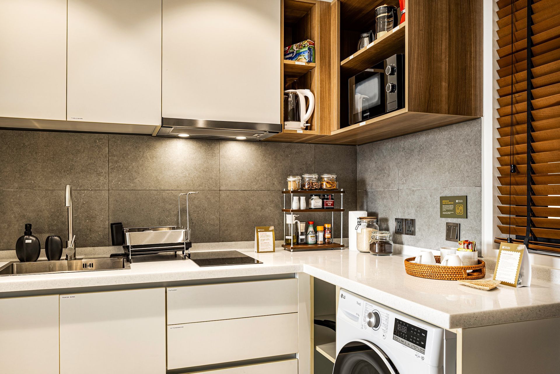 Modern kitchen with white cabinets, countertop appliances, and a washer beneath the counter