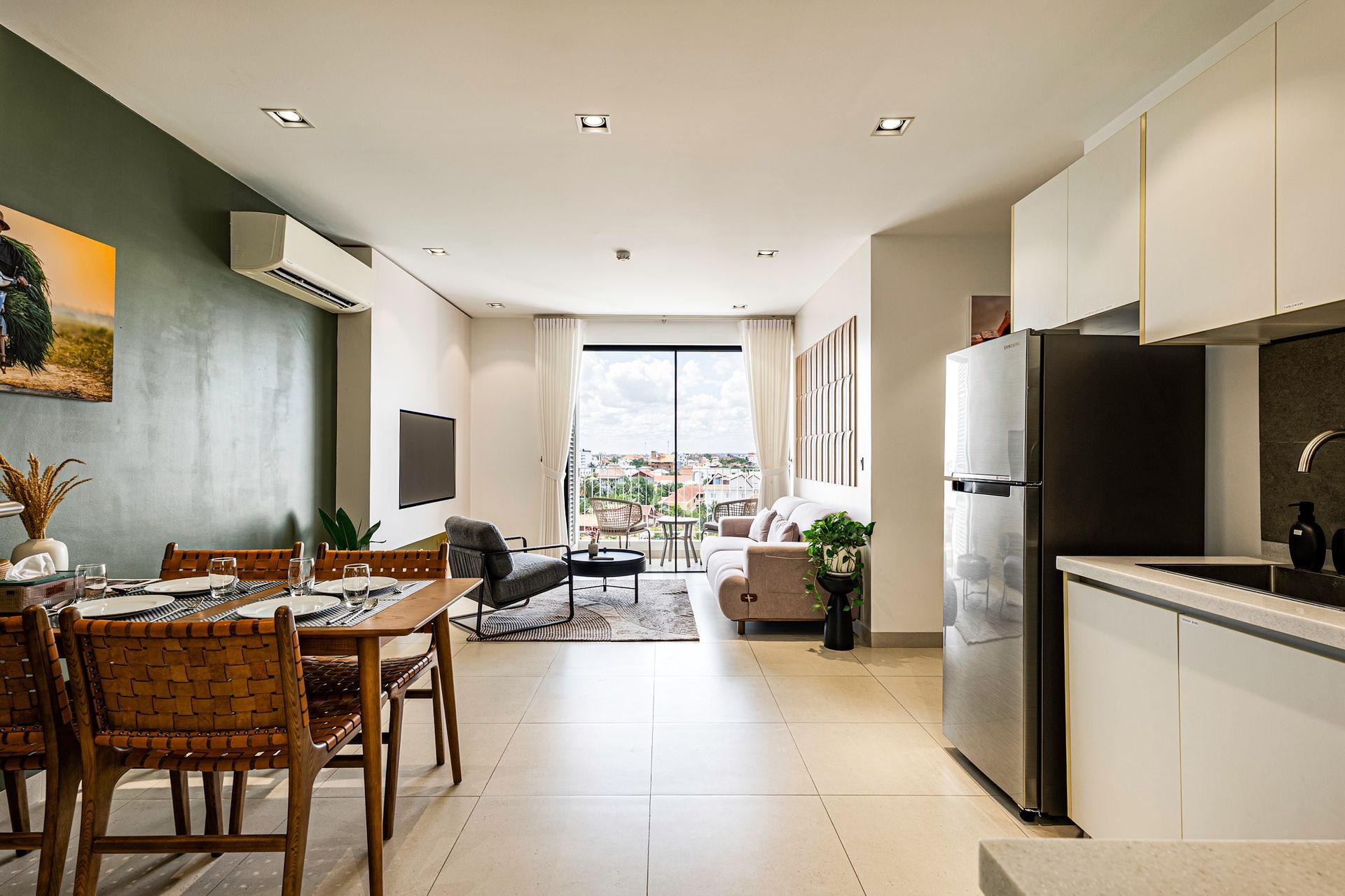 Modern open-plan apartment with kitchen, dining area, and living room leading to a balcony.