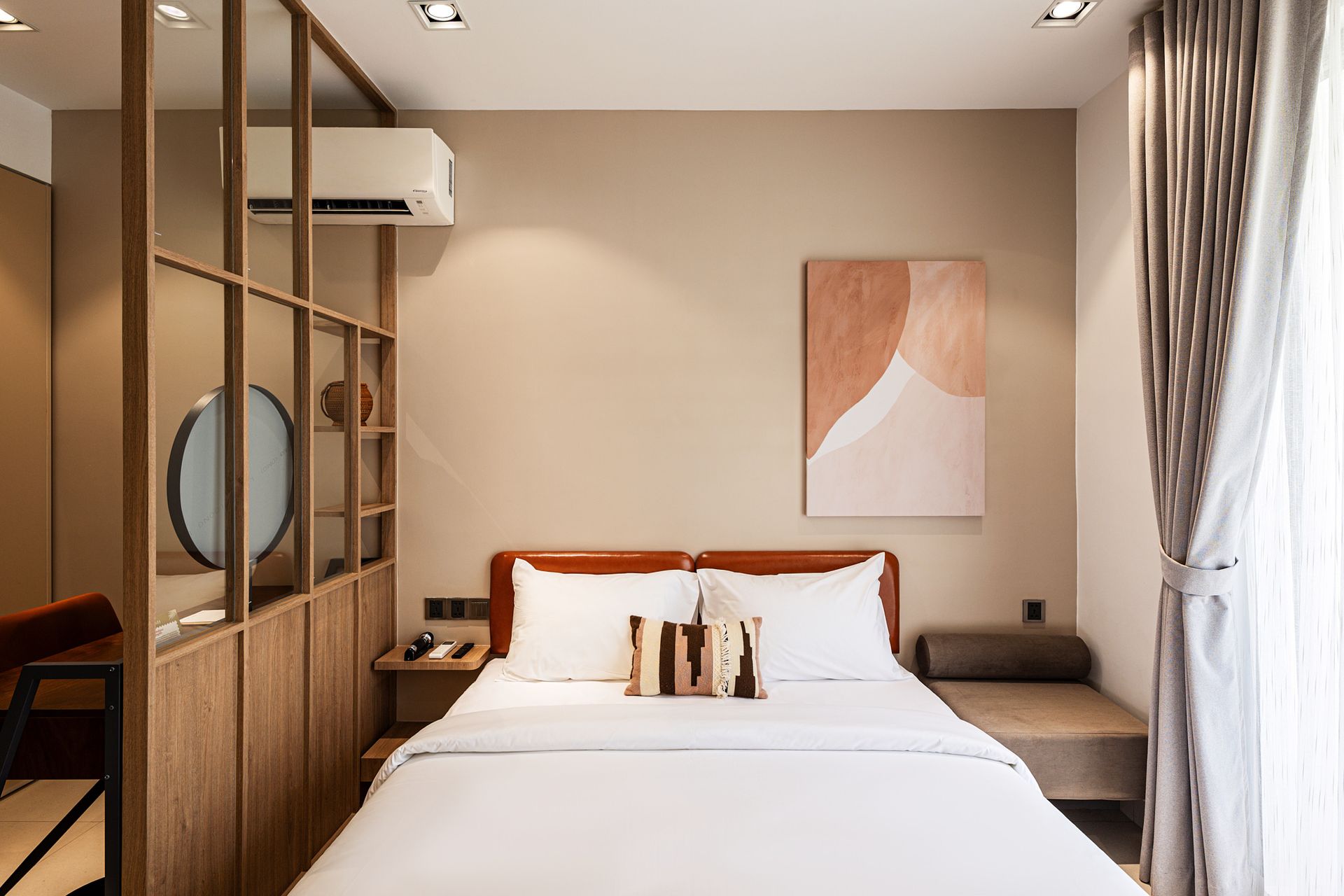 Modern bedroom with a neatly made bed, wood shelving, and sheer curtains by a bright window