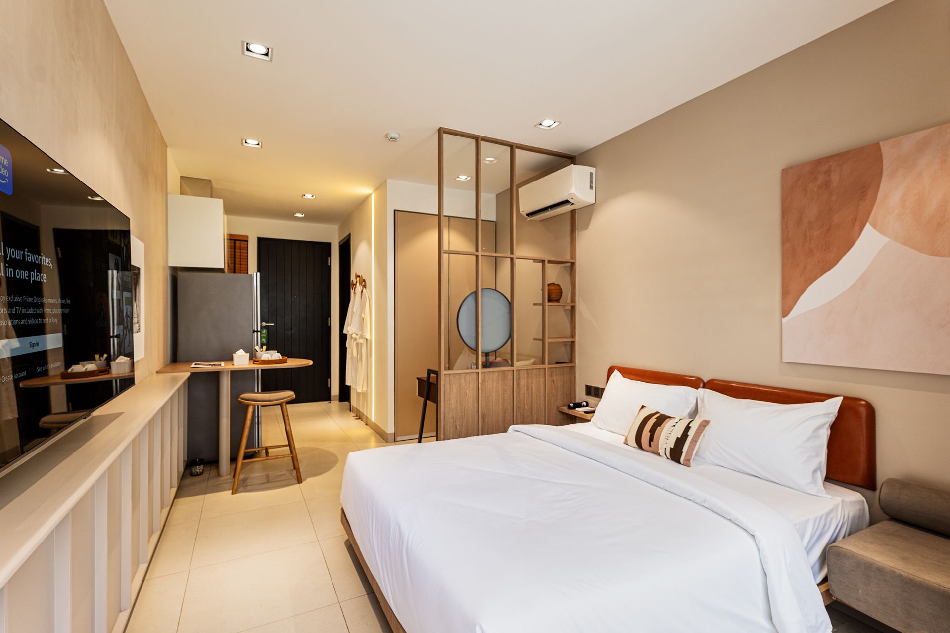 Modern hotel room with a bed, desk, wood accents, and warm lighting