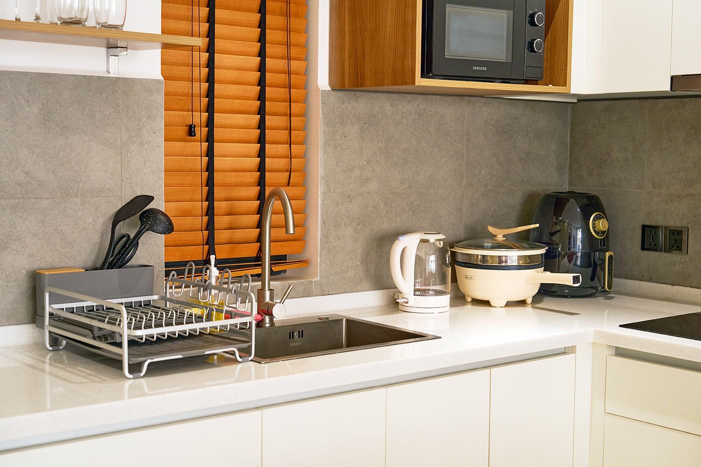 Modern kitchen with white cabinets, stainless steel refrigerator, microwave, and sink.