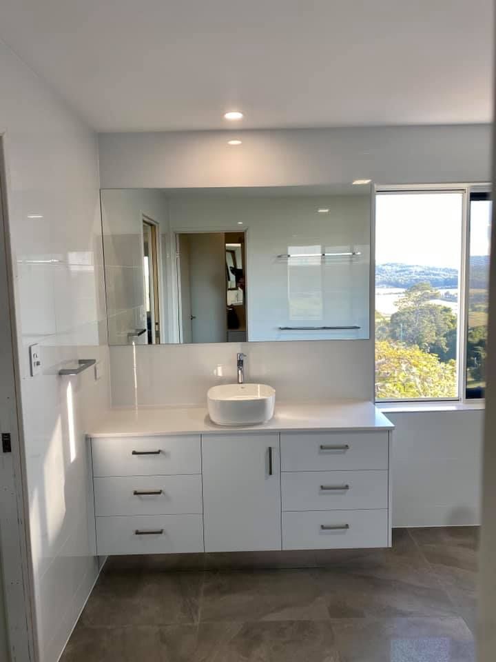 A Bathroom With a Sink, Mirror and Window — NGK Constructions In Freshwater, QLD