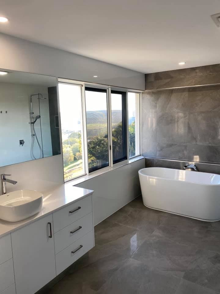 A Bathroom With a Tub, Sink, Mirror and Window — NGK Constructions In Freshwater, QLD