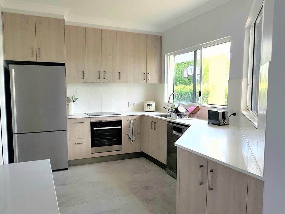 A Kitchen With Stainless Steel Appliances and Wooden Cabinets — NGK Constructions In Freshwater, QLD