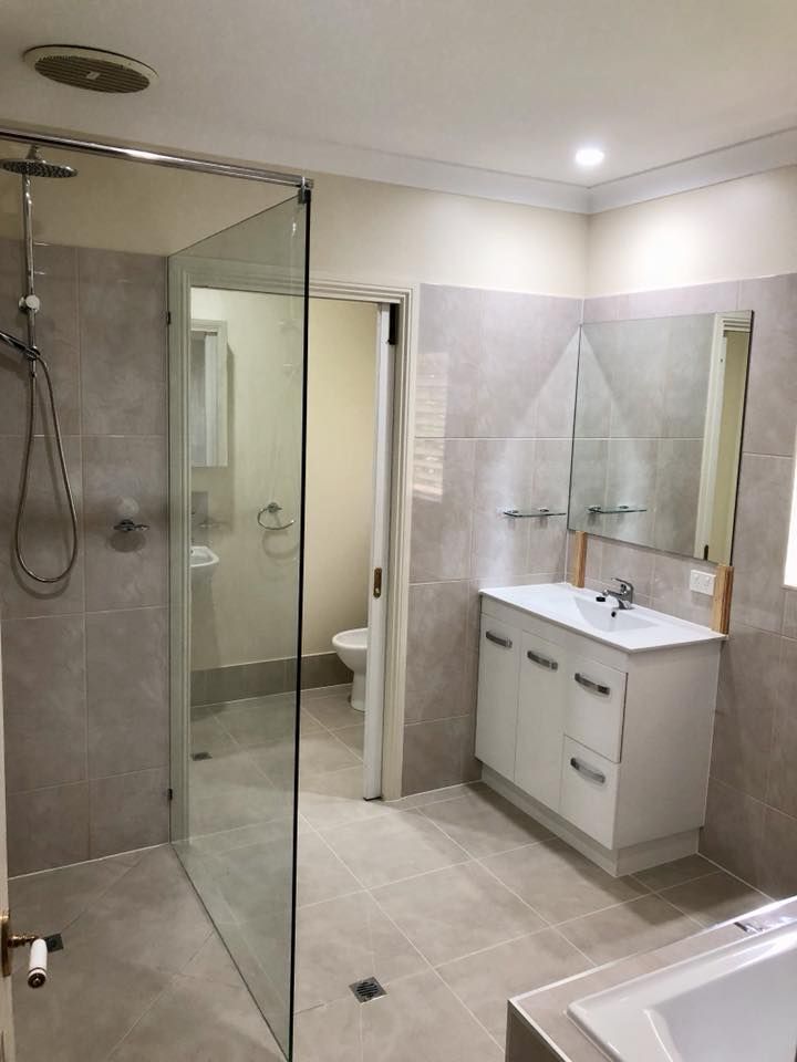 A Bathroom With a Walk in Shower, Sink and Mirror — NGK Constructions In Freshwater, QLD