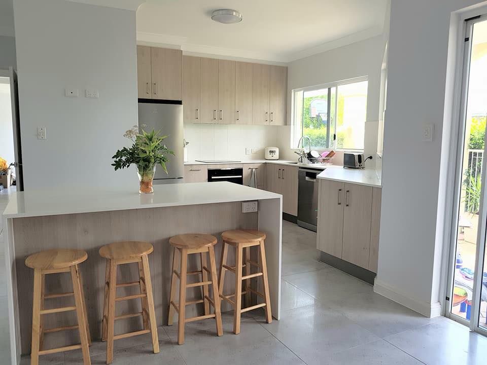 A Kitchen With Wooden Stools and a White Counter Top — NGK Constructions In Freshwater, QLD