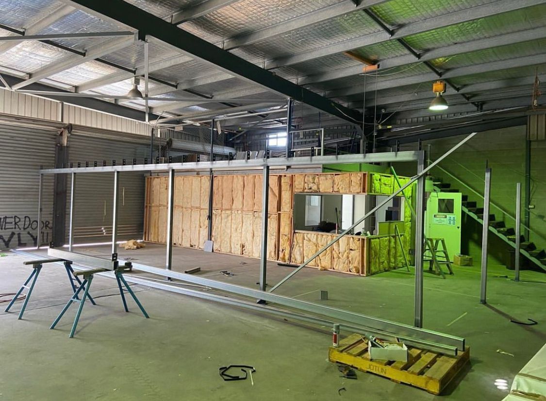 A Large Empty Warehouse With a Green Roof and Stairs — NGK Constructions In Freshwater, QLD