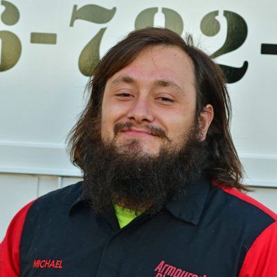 Smiling bearded man in a black and red uniform shirt standing outdoors