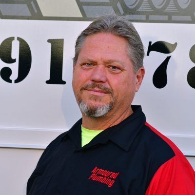Man in black and red shirt standing in front of a numbered wall, smiling at the camera