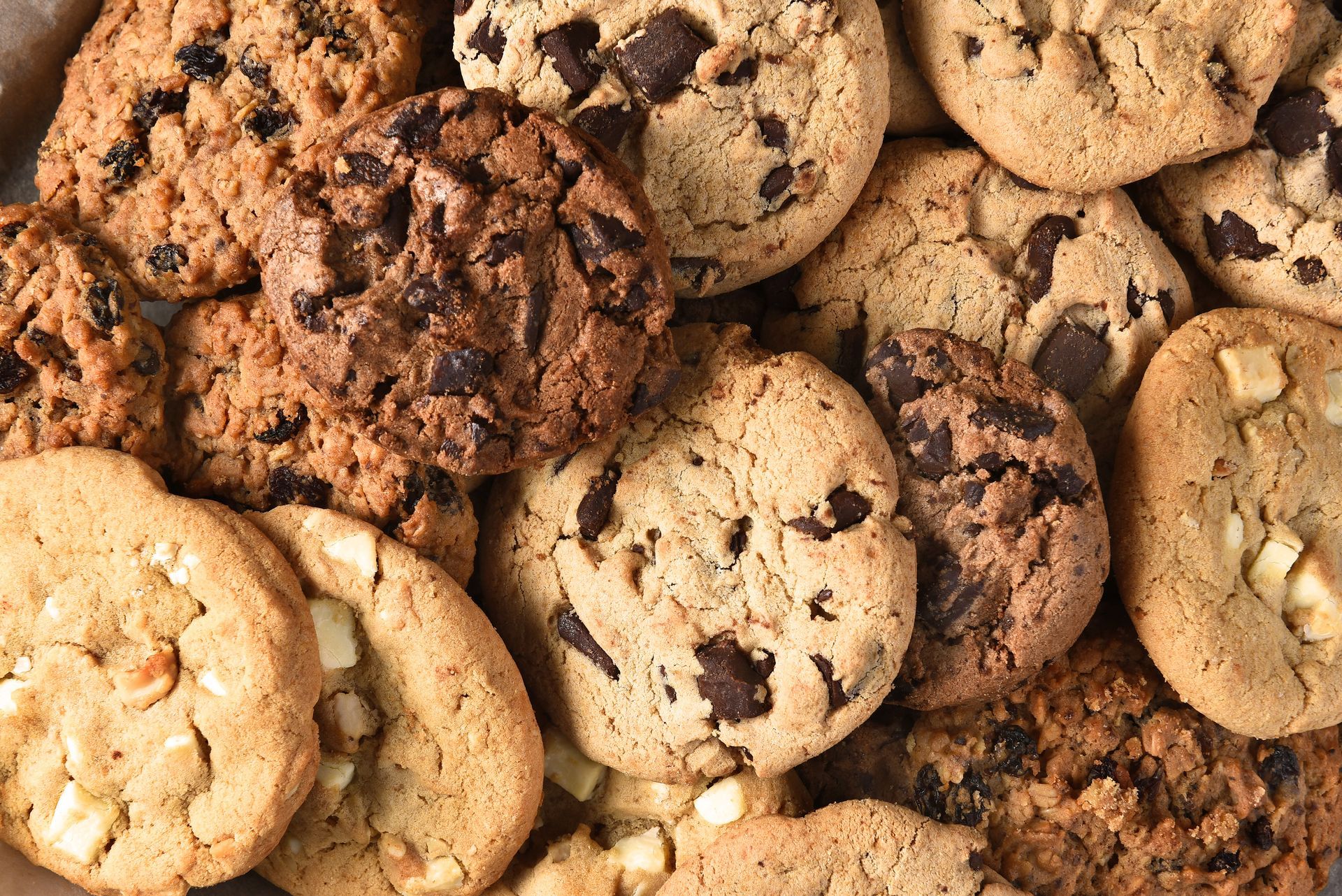 Assorted chocolate chip cookies piled together, with golden and dark brown baked tops.