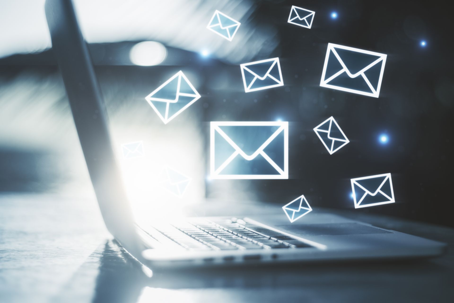 Laptop with glowing email icons floating above the keyboard, suggesting digital communication or email marketing