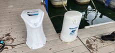 Two white water filters on a wooden dock next to water.