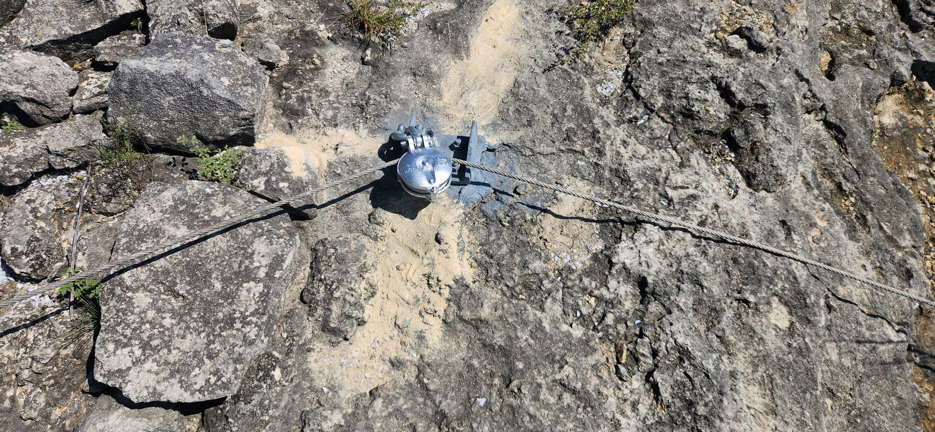 A small metallic object is set in a crack on a rocky surface.