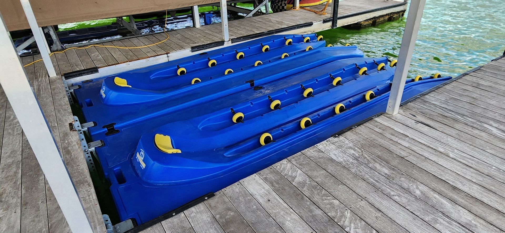 Blue floating dock on a wooden dock near water.