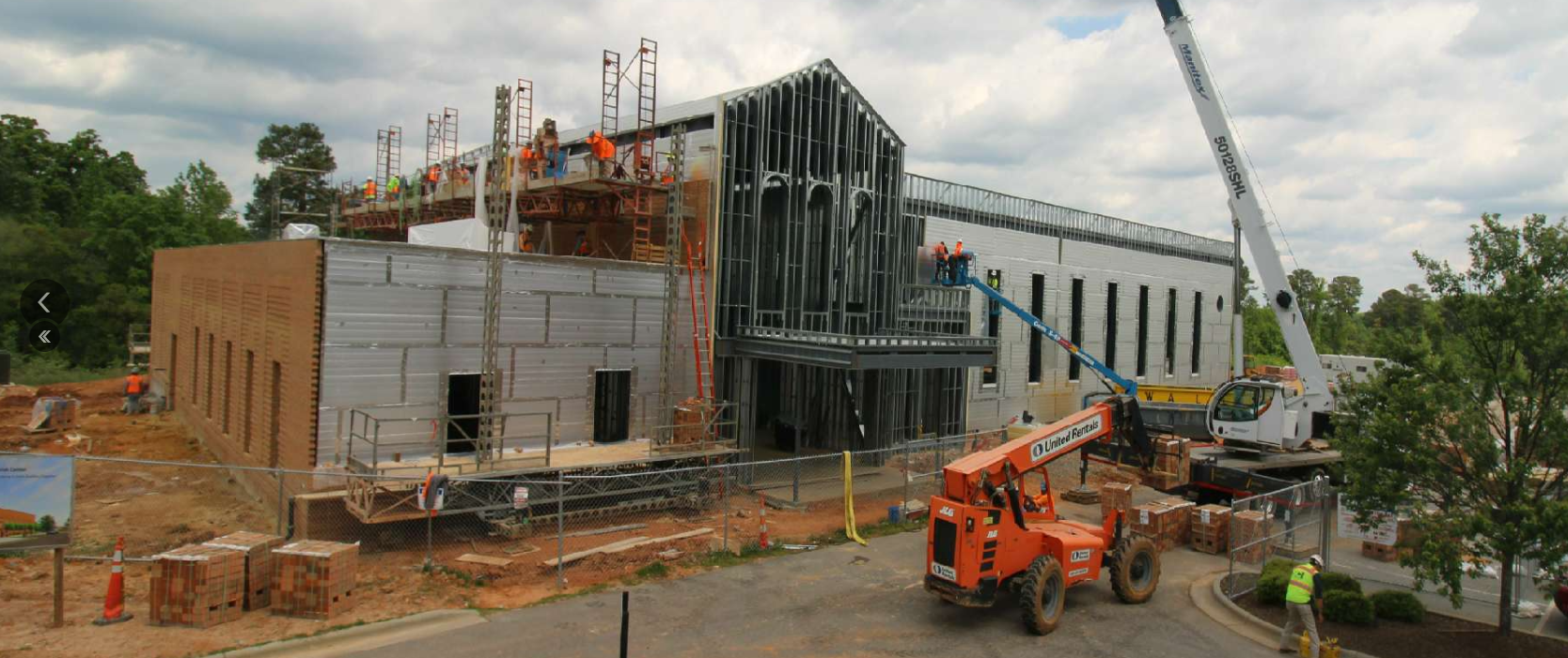 A large building under construction with a jlg crane in front of it