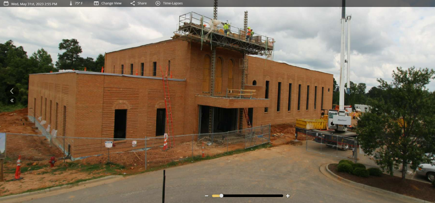 A large brick building under construction with a crane in front of it
