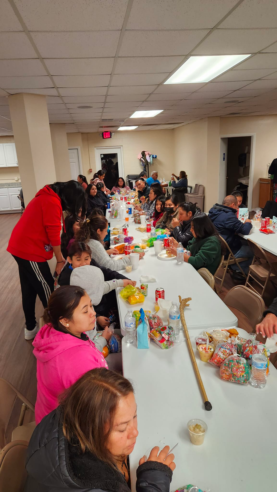 A group of children are sitting at long tables in a room.