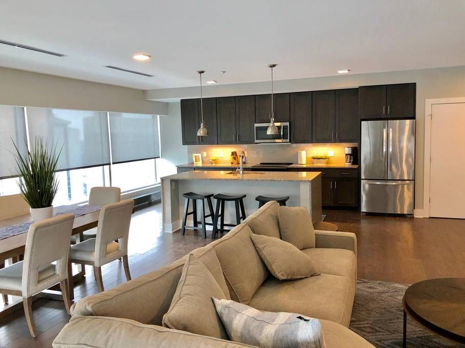 Open-concept kitchen and living area with dark cabinets, island, and stainless steel appliances.
