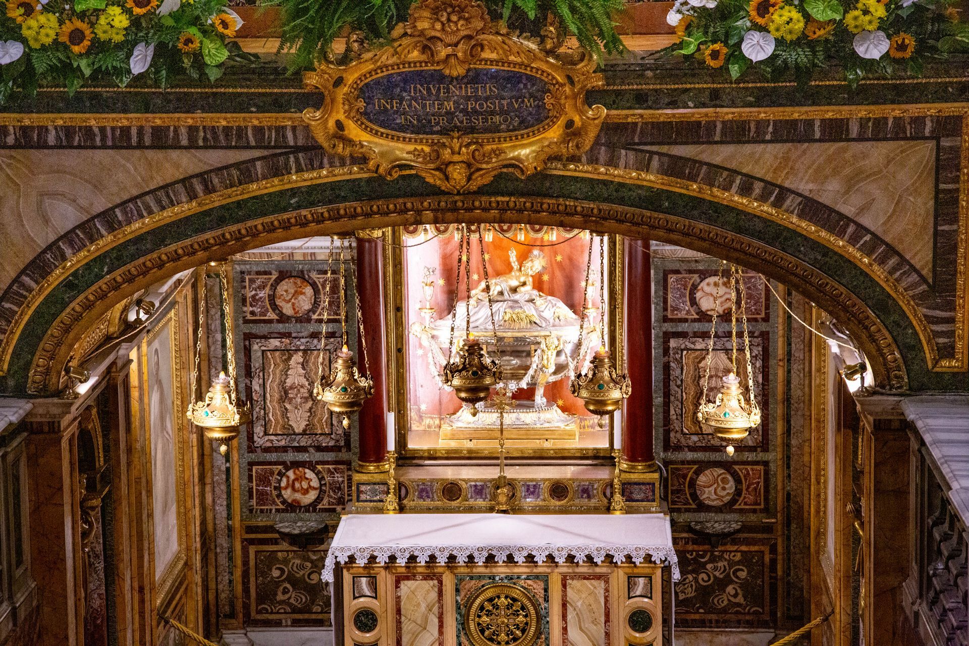 Ornate altar with a gold-framed religious icon, candles, and carved wood under a decorated archway