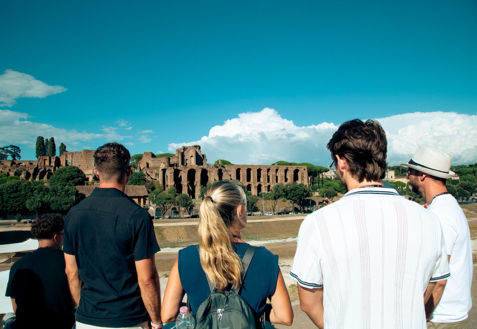 Tourists standing above the Circus Maximus looking at the Palatine Hill.