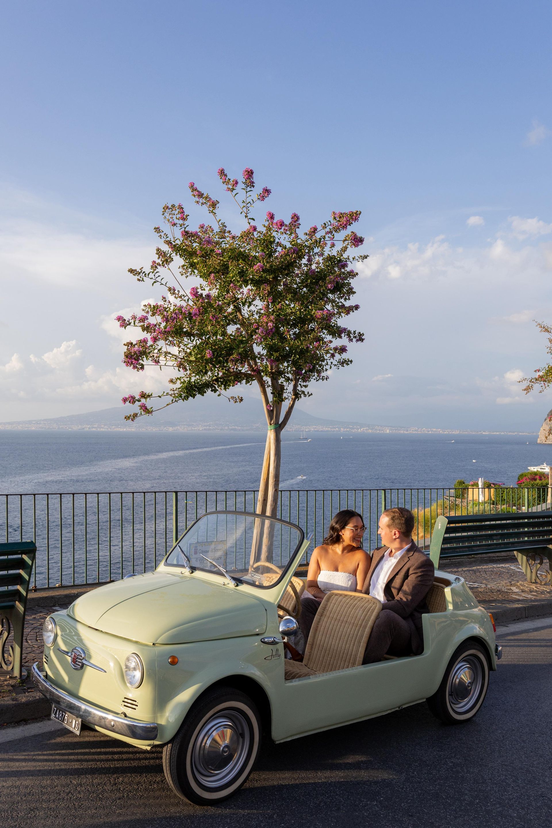Couple posing in a Fiat 500 on the Amalfi Coast road.