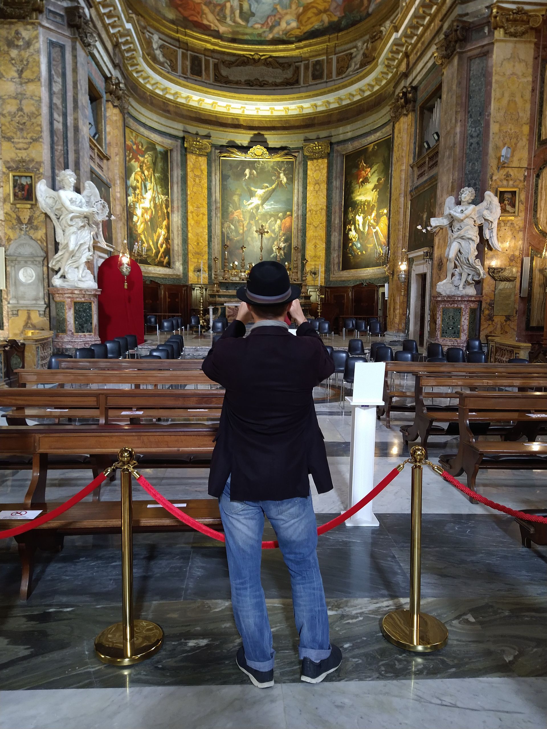 Person in hat taking photo inside ornate church.