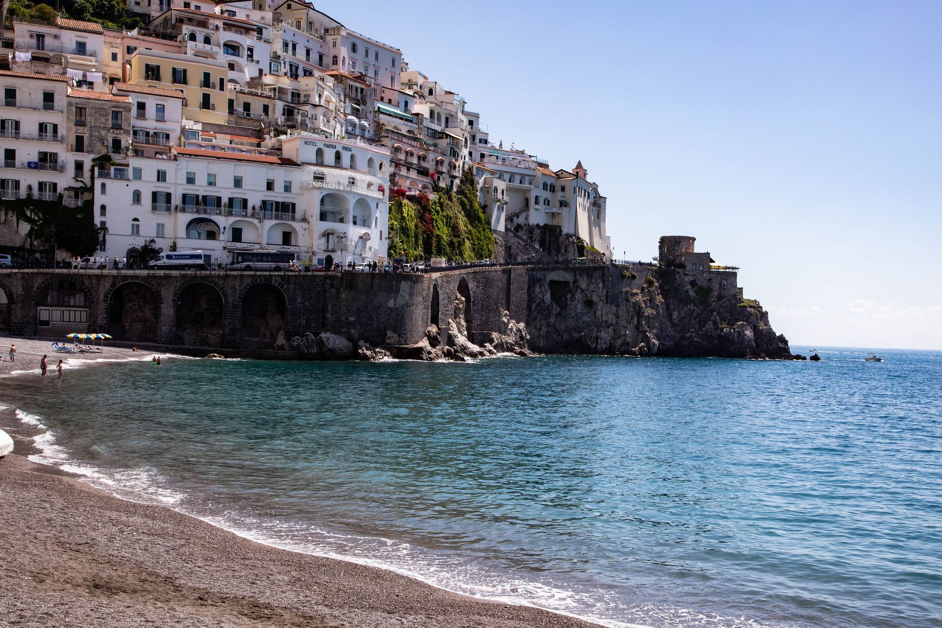 Cliffside coastal town with white buildings overlooking a pebble beach and blue sea
