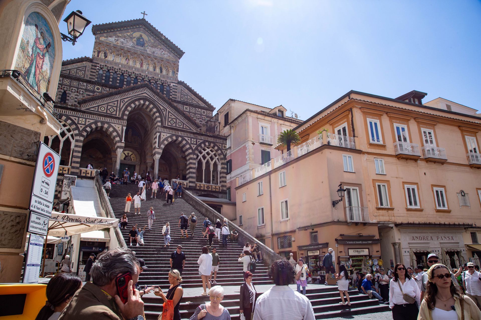 Crowded steps leading to a striped cathedral façade in a sunny Amalfi square
