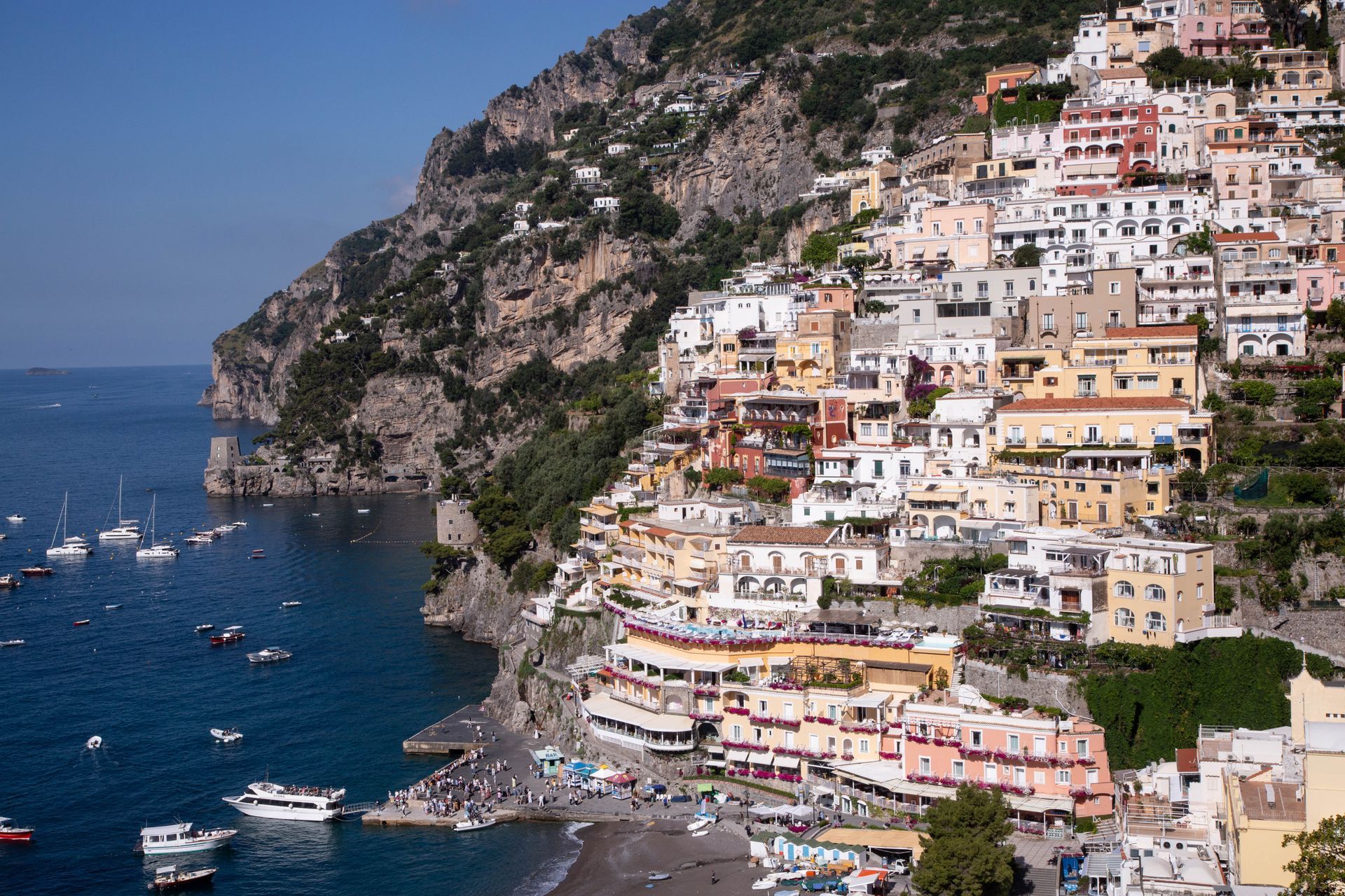 Colorful cliffside village overlooking a blue sea with boats below in Capri, Italy.
