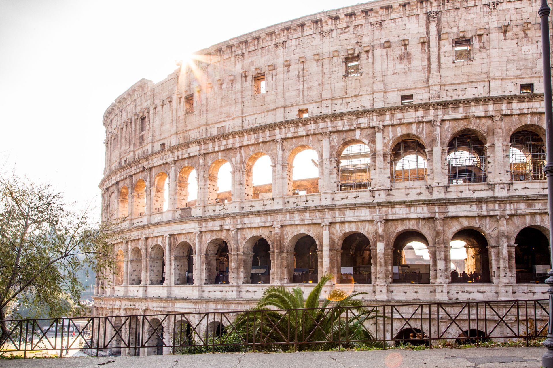 Arch of Constantine and Colosseum in Rome at dusk, cobbled road, trees, and cloudy sky.