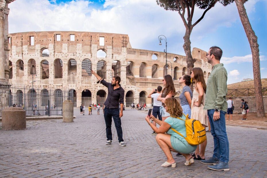Tour guide pointing at the Colosseum in Rome to a group of tourists.