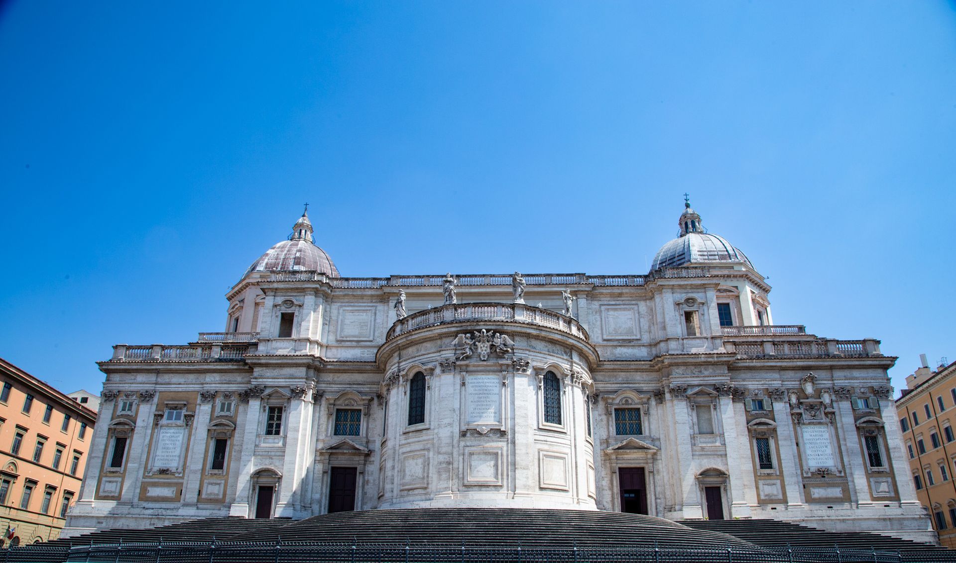 Grand white stone cathedral facade under a bright blue sky