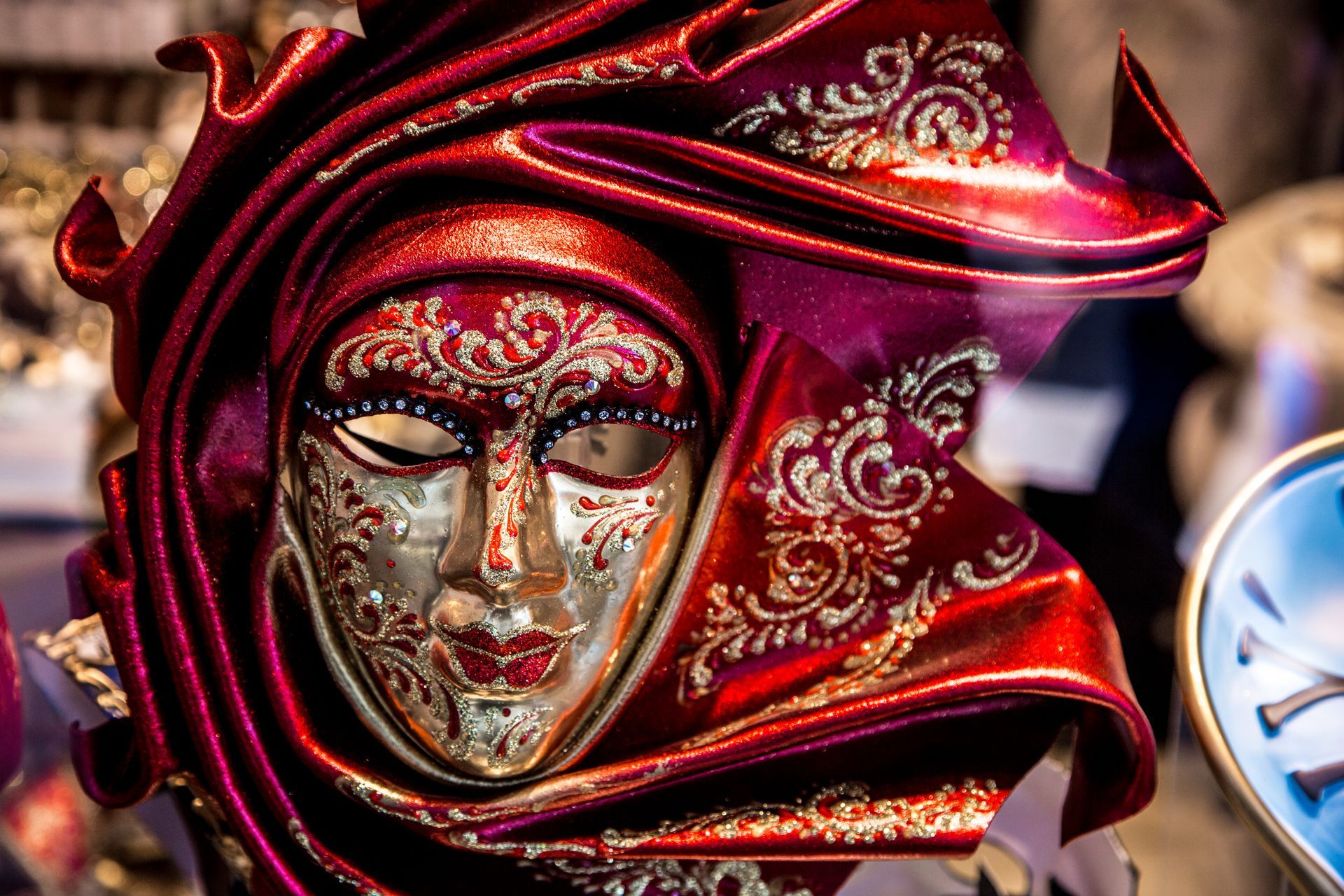 Ornate red and gold Venetian mask with sequined details and a matching hat