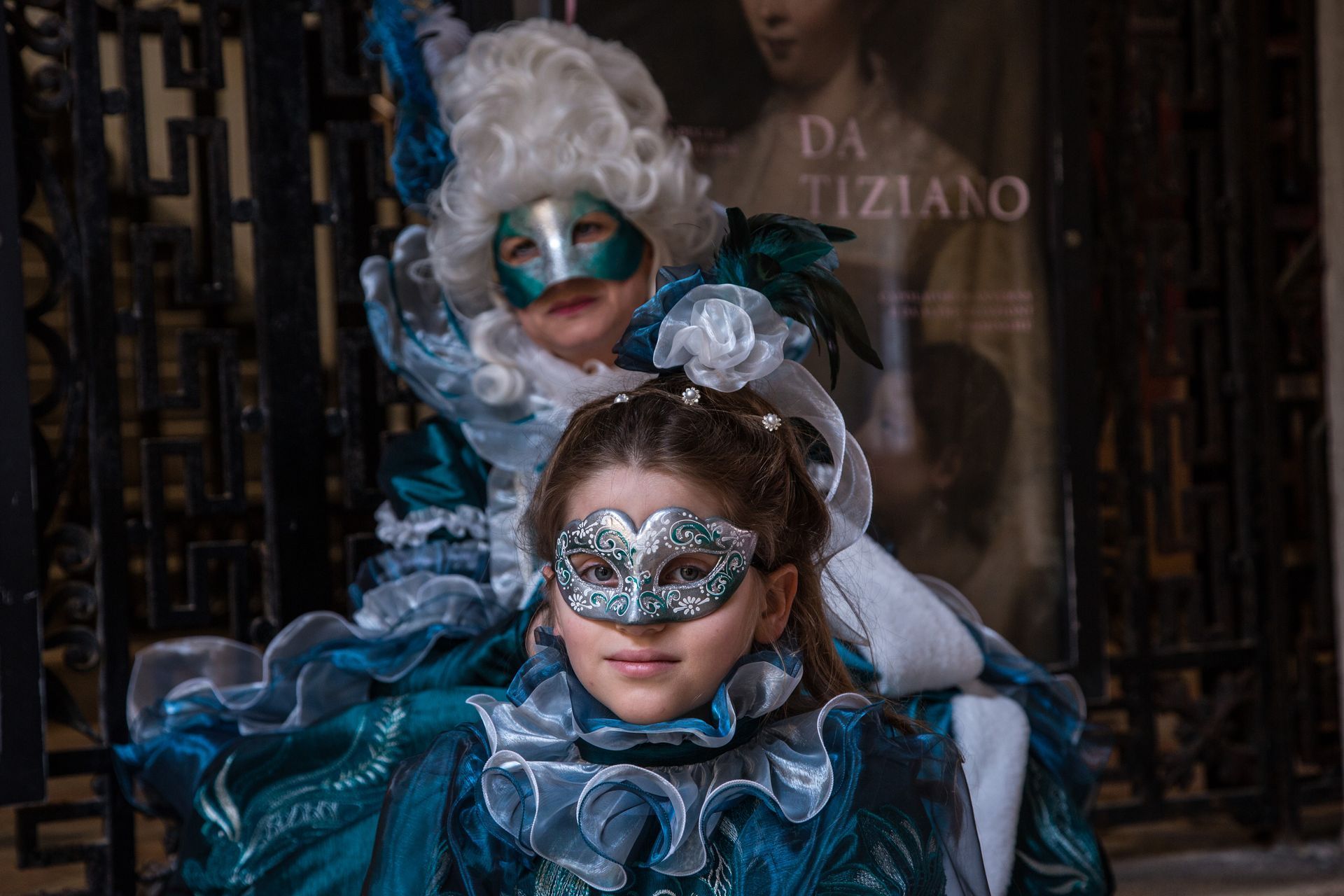 Two masked performers in ornate blue costumes pose in a dim, theatrical setting.