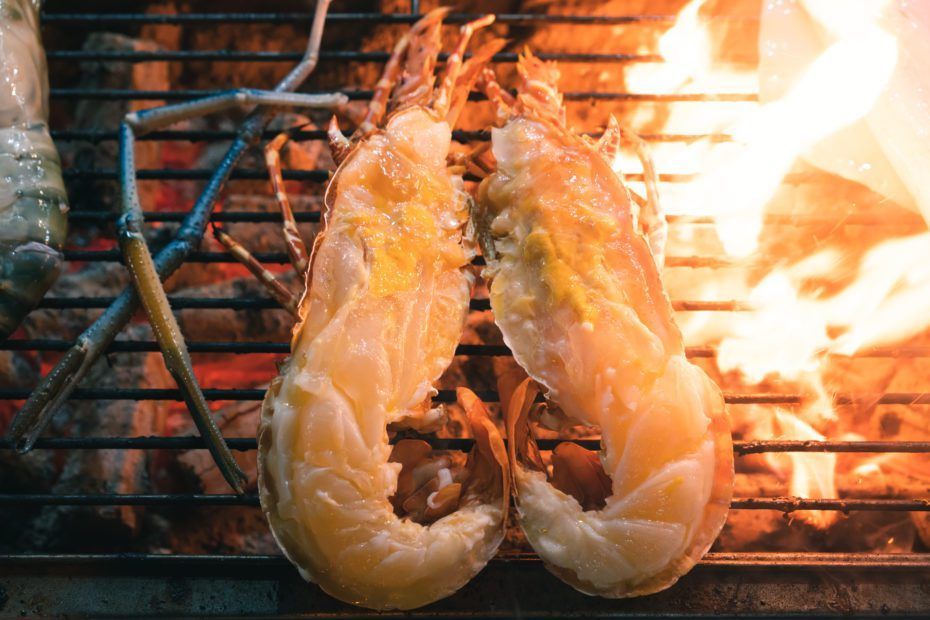 Grilled lobster halves on a hot grill with flames.