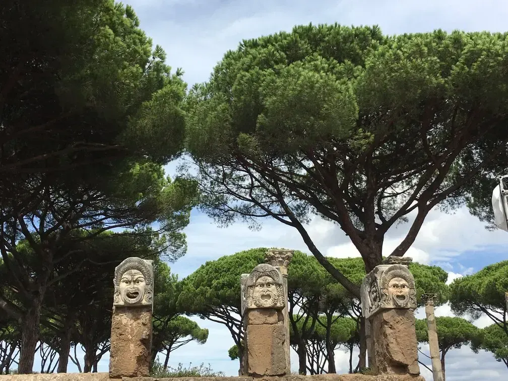 Three ancient stone masks with trees in the background. Blue sky, sunny day.