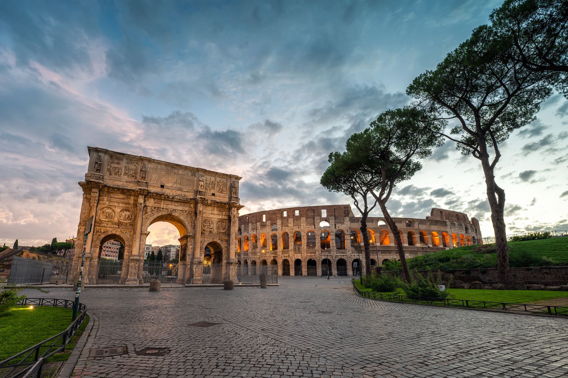 Interior view of the Colosseum in Rome, Italy, with ruins of arches and passageways. Two people stand on a viewing platform.