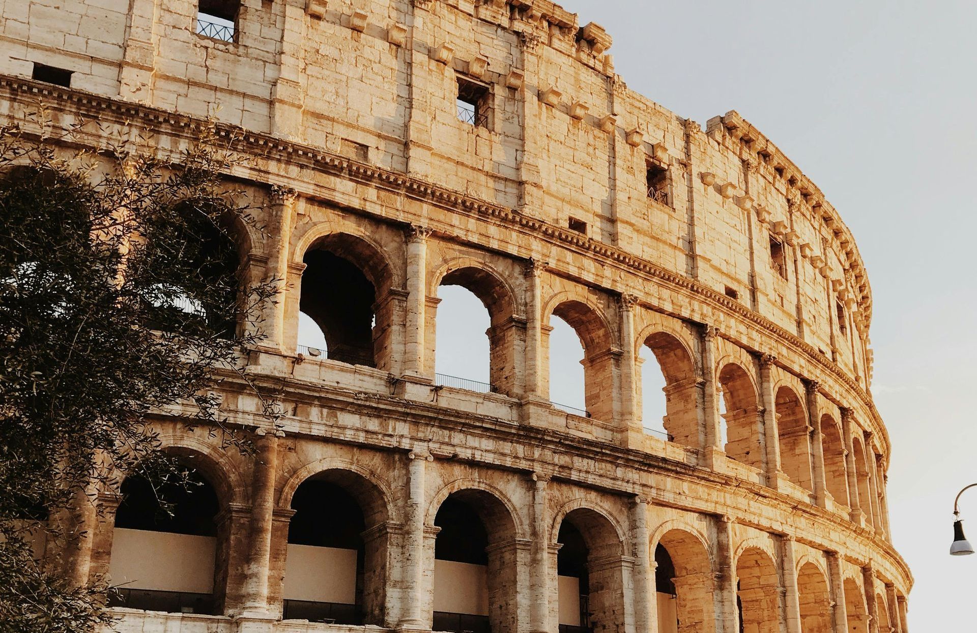 Colosseum, Rome, Italy, bathed in golden sunlight, showcasing arched levels of stone.