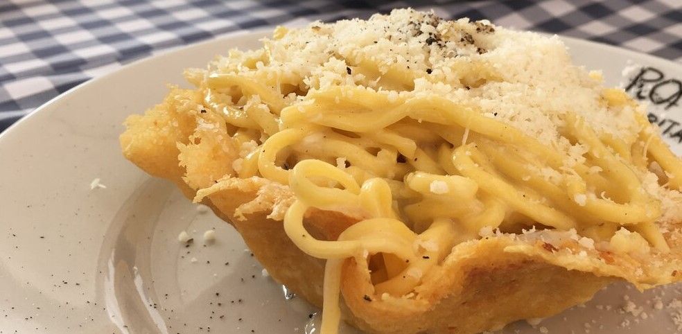 Spaghetti carbonara served in a crispy Parmesan cheese bowl on a white plate.
