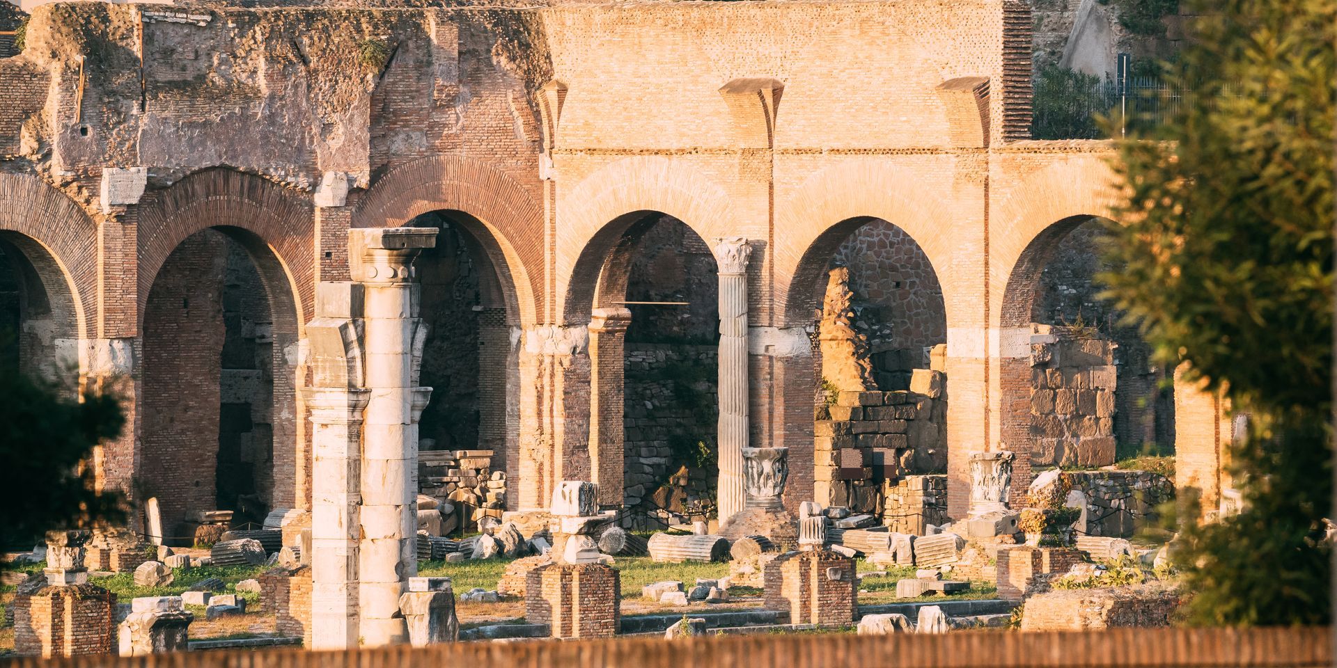 Ancient Roman ruins with arched columns, some partially standing. Brown and beige tones.
