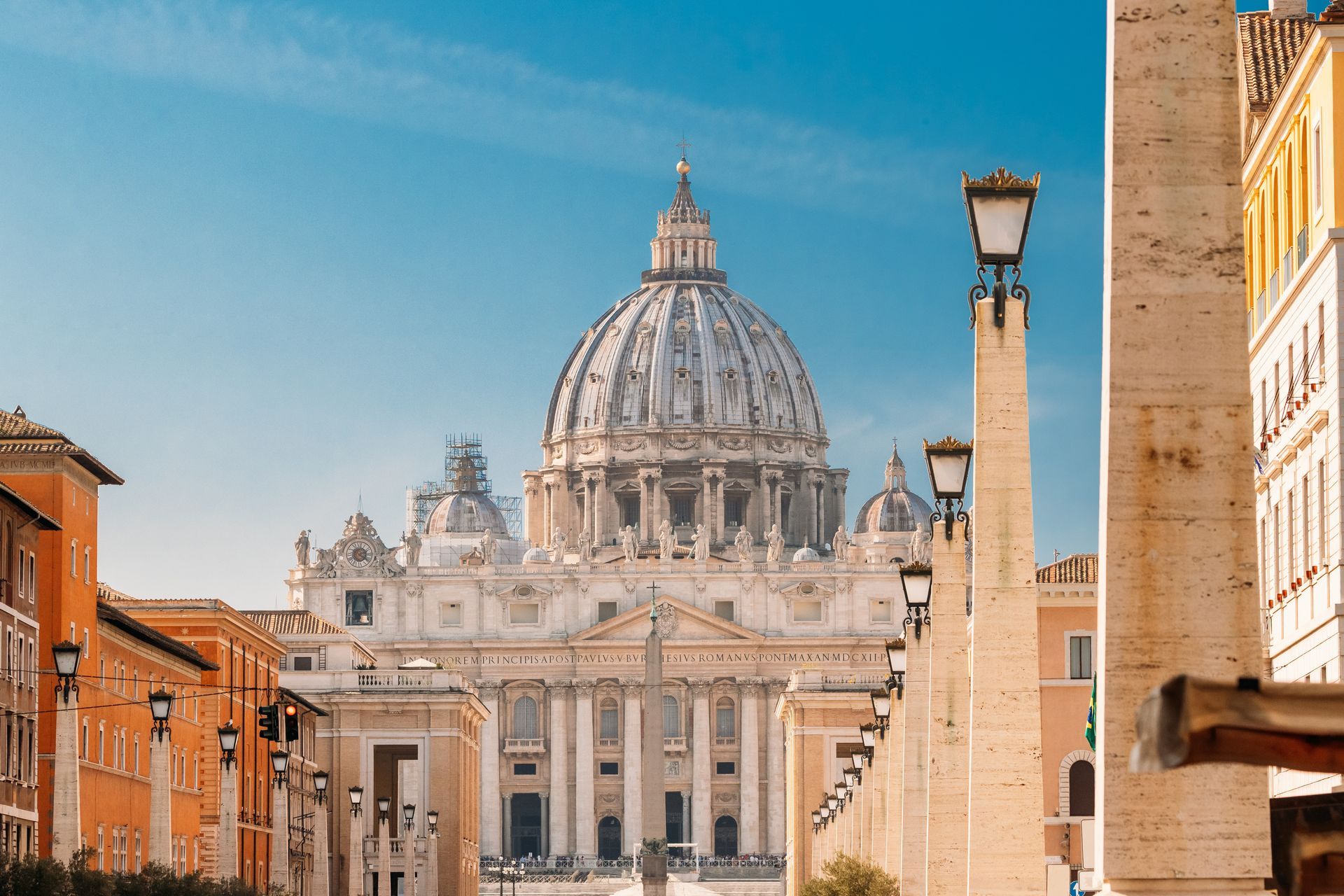 St. Peter's Basilica in Vatican City, seen from street; dome rises against blue sky.