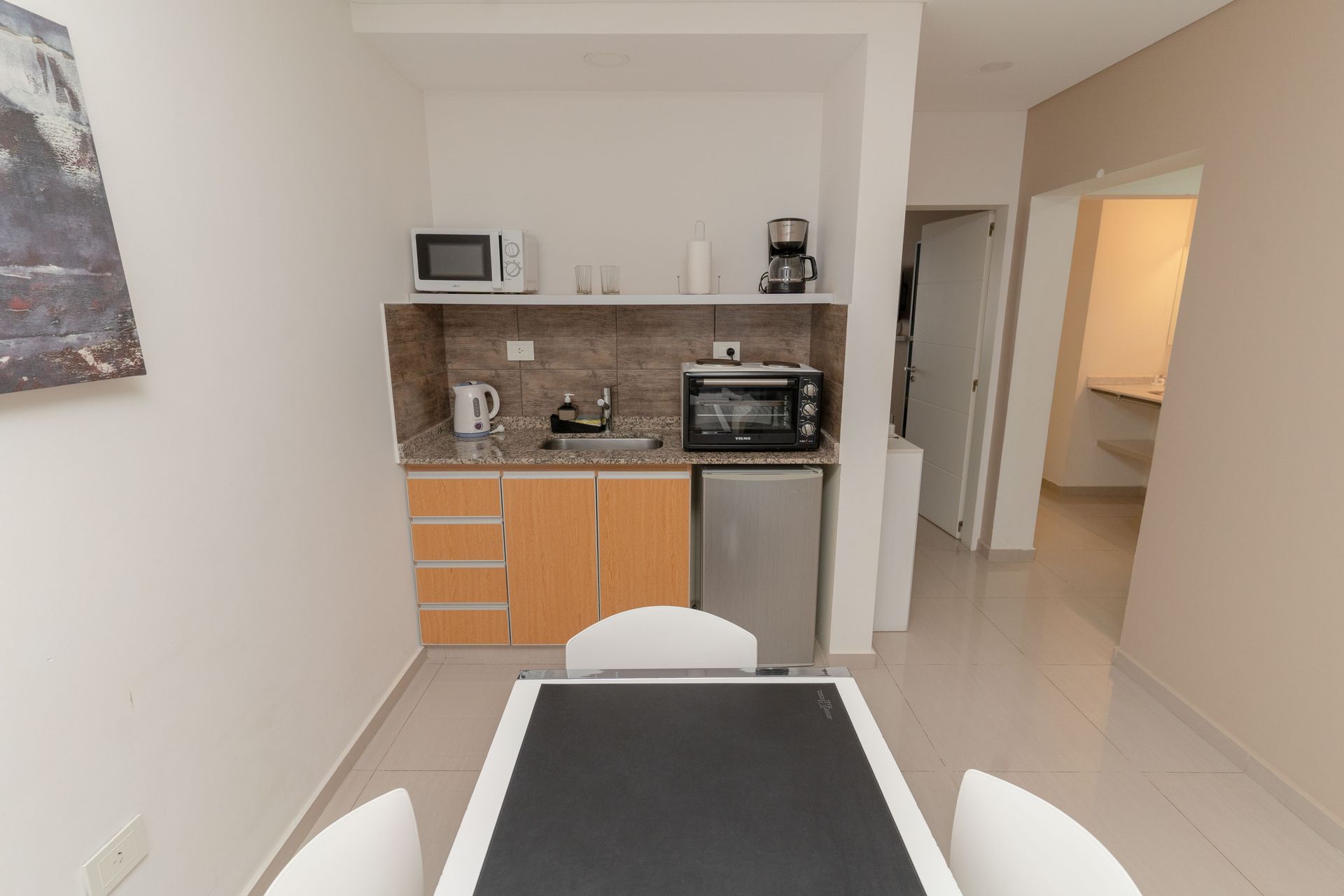 Small kitchen and dining area with cabinets, appliances, and a table with chairs.