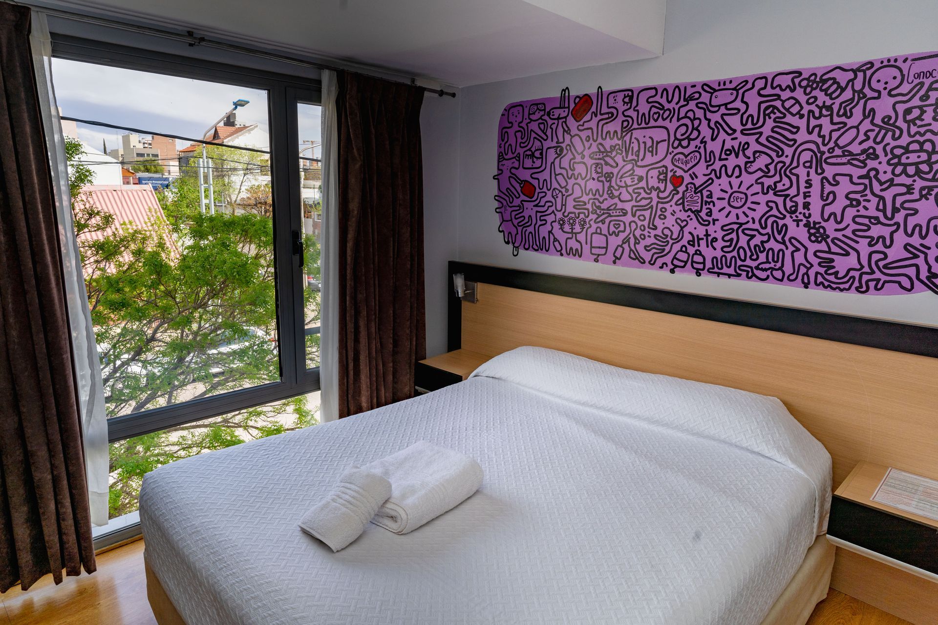 Bedroom with a bed, large window, and purple art on the wall.