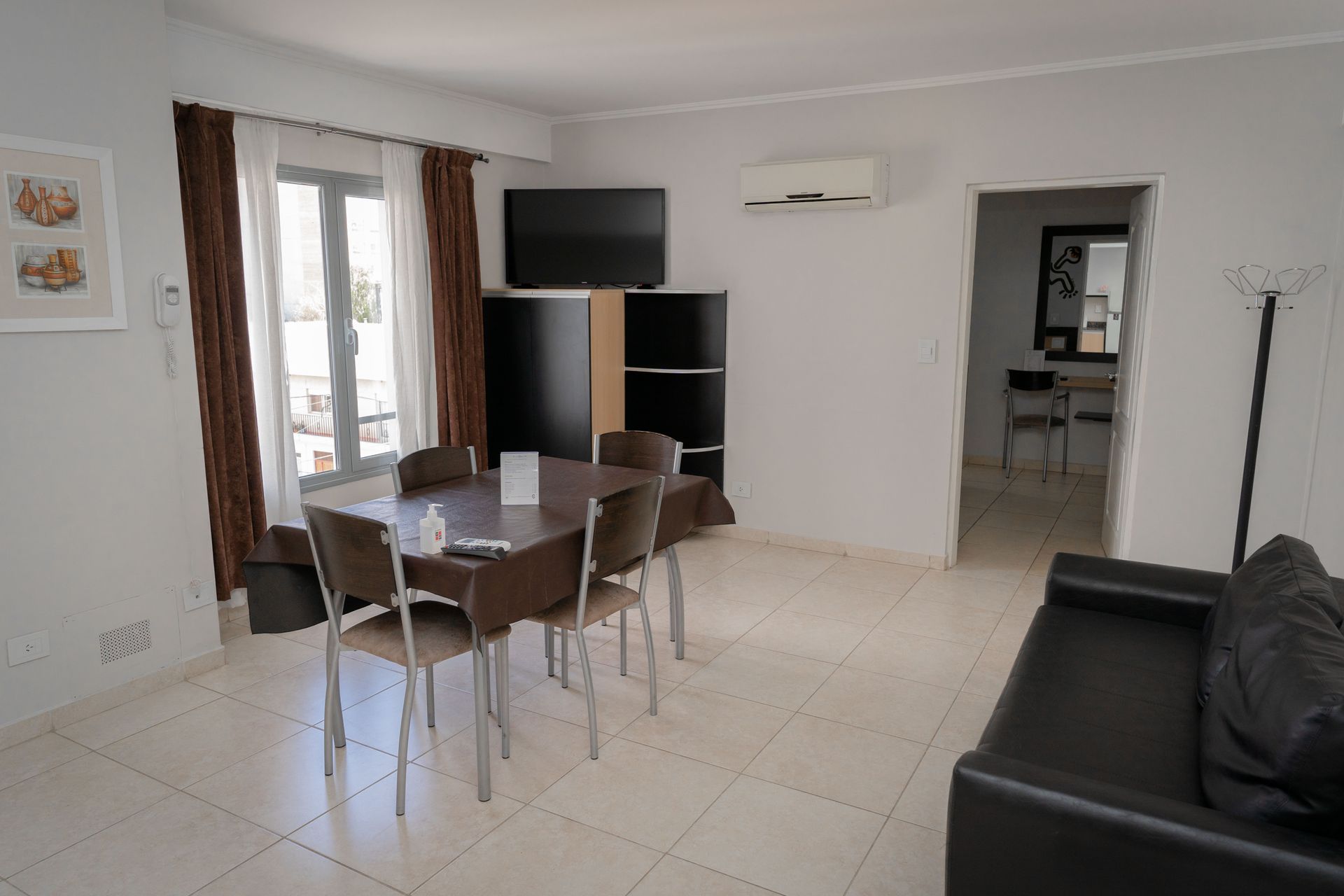 Living room with dining table, sofa, TV, and access to a hallway and balcony.