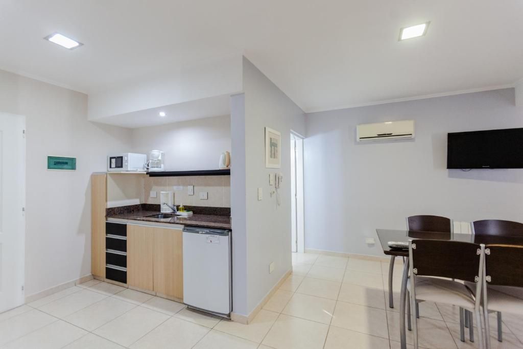 Small apartment interior with kitchenette, dining area, and television; neutral colors.