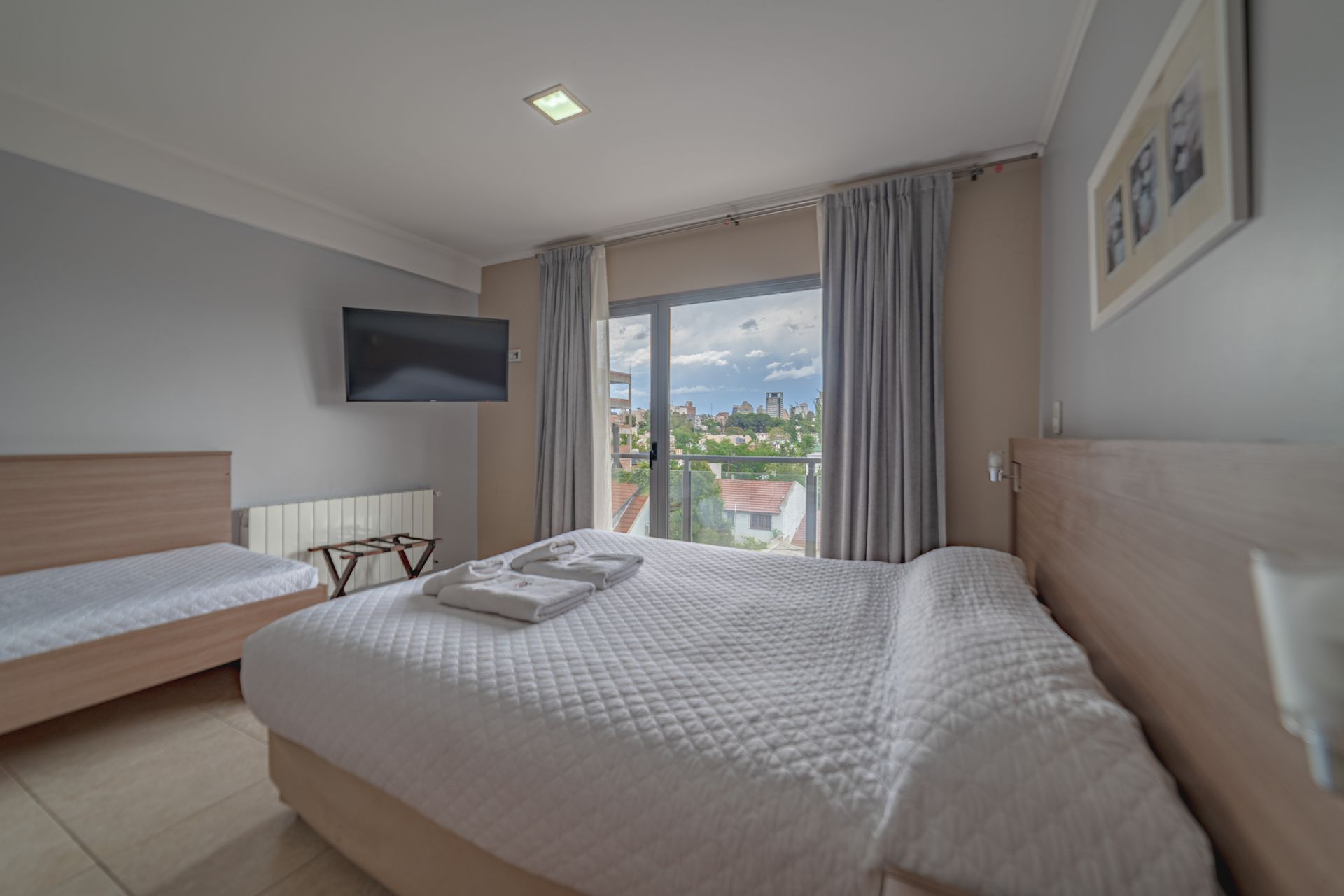 Hotel room with a large bed, single bed, TV, and balcony view.