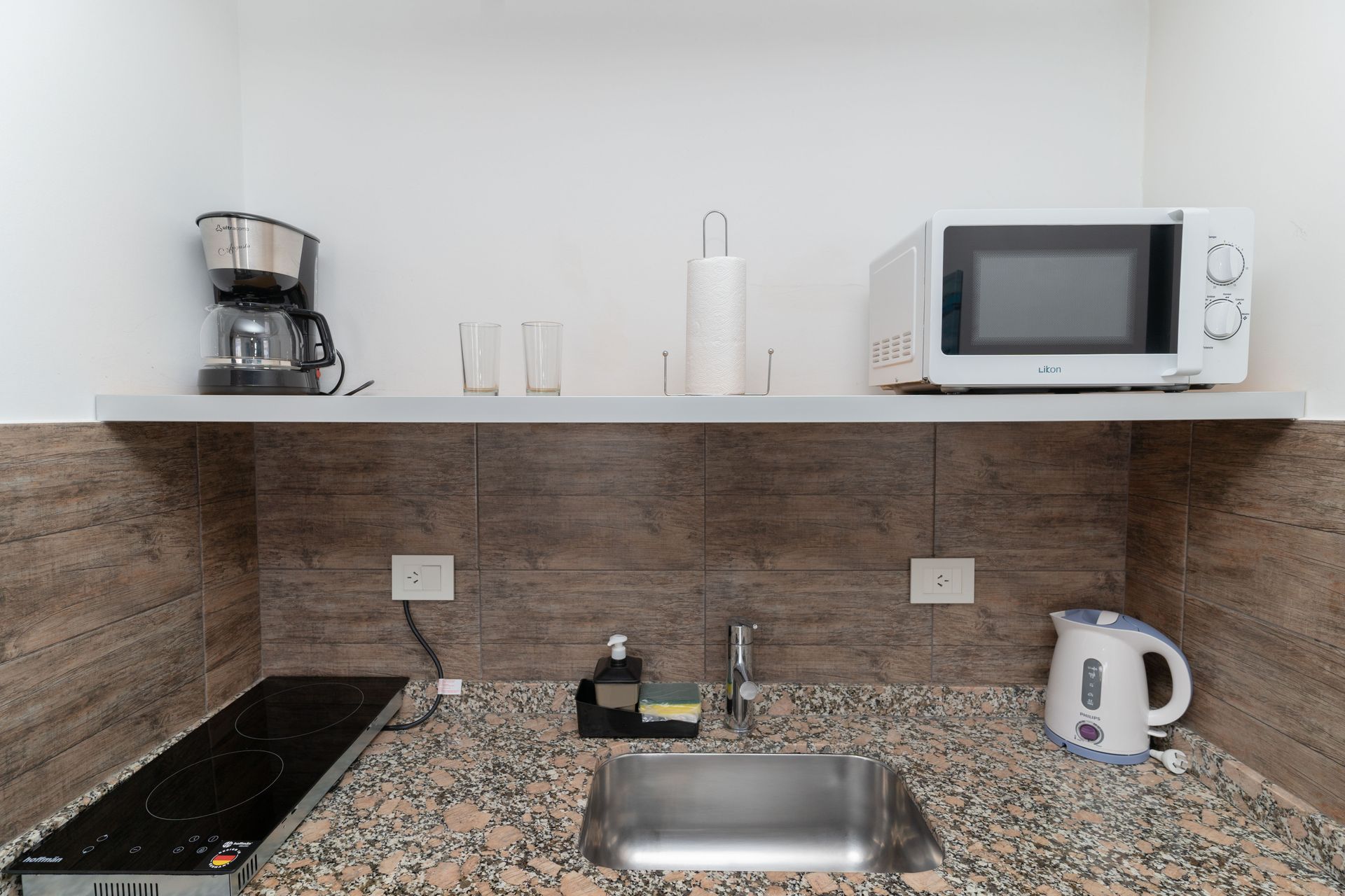 Small kitchen area with microwave, coffee maker, sink, and electric kettle.