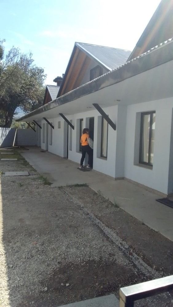 Exterior of white buildings with black beams and a pathway; people stand in the open doorway.